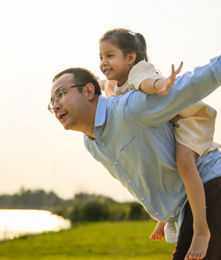 Father carrying child on his back while smiling outdoors